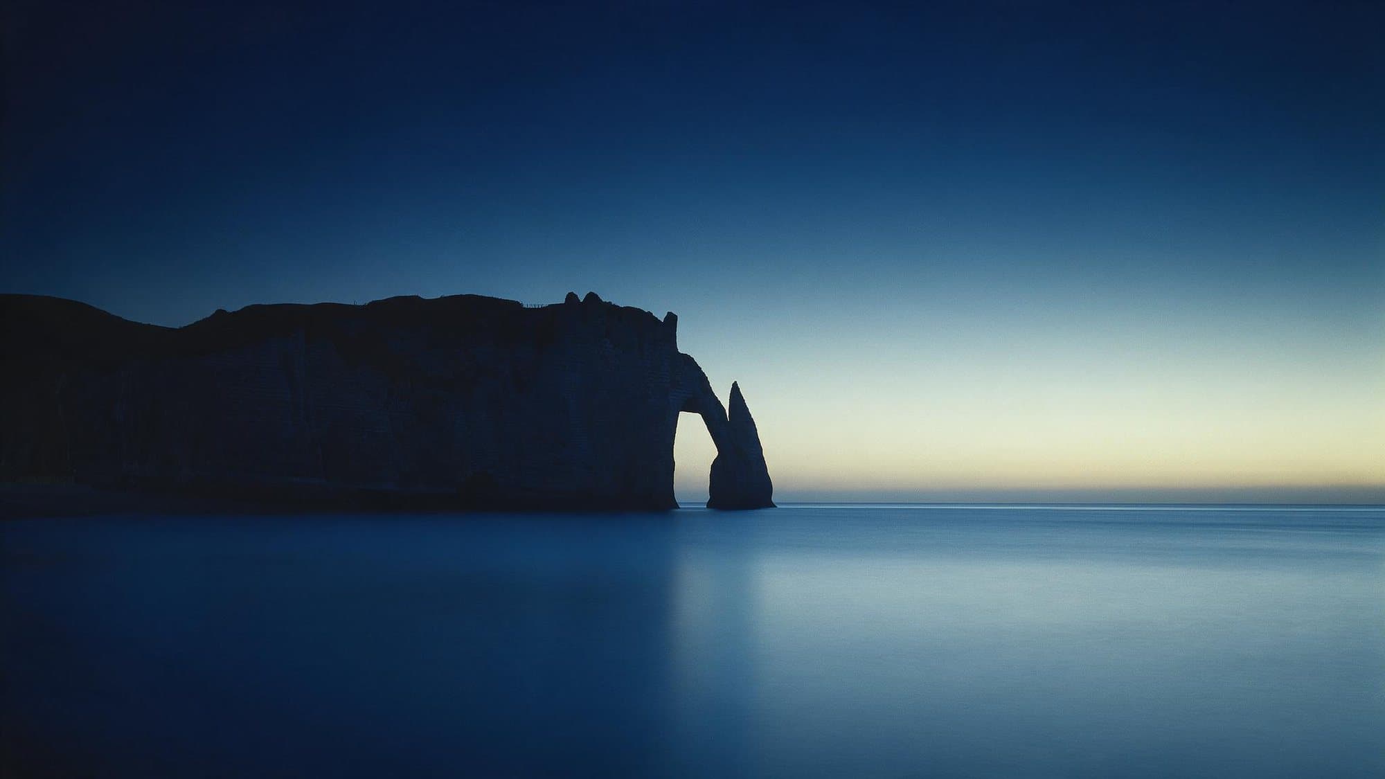 Les falaises d'Étretat à l'aube, l'Aiguille et la Porte d'Aval en silhouette