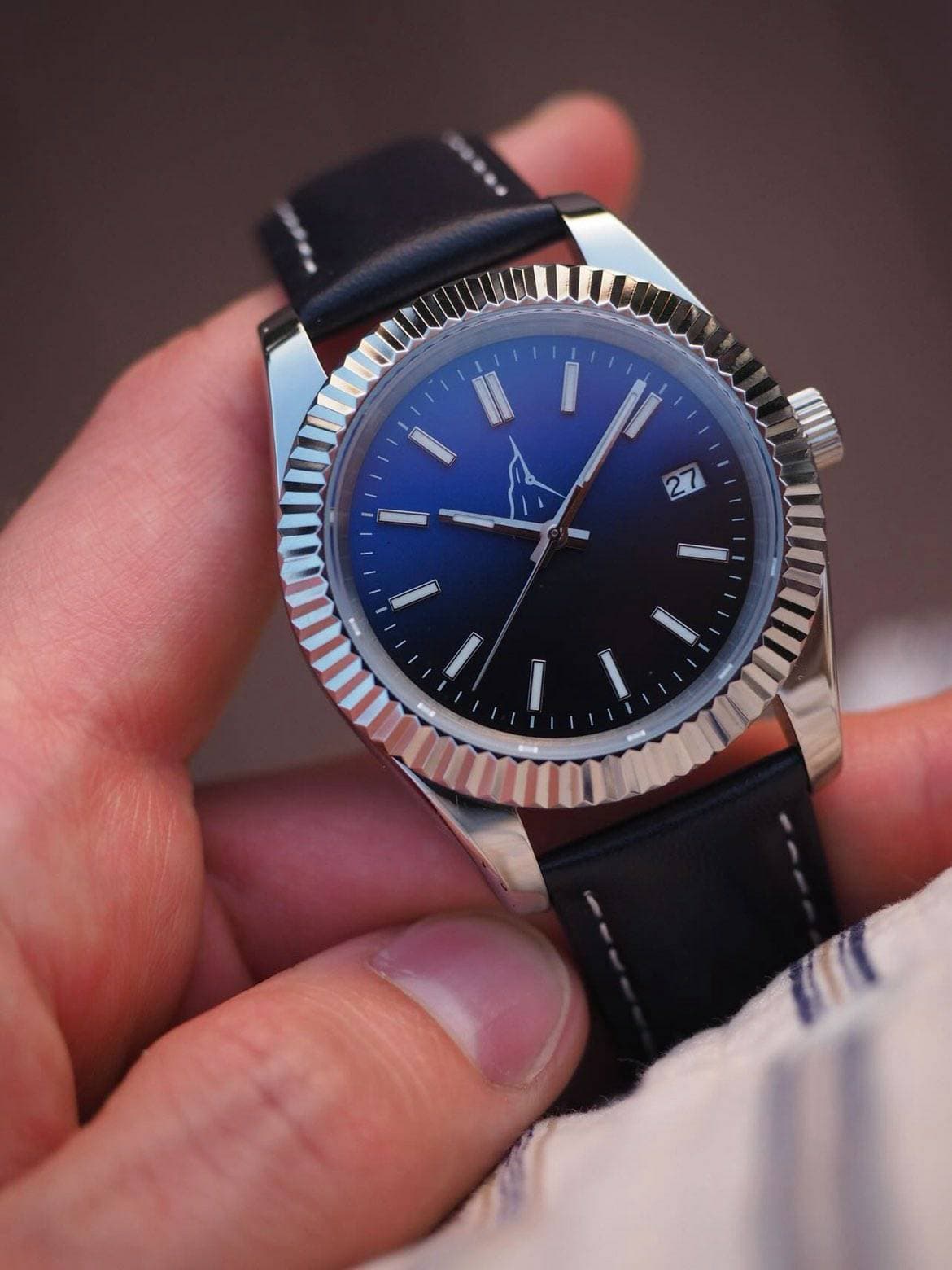 Cadran bleu soleillé et lunette cannelée en gros plan